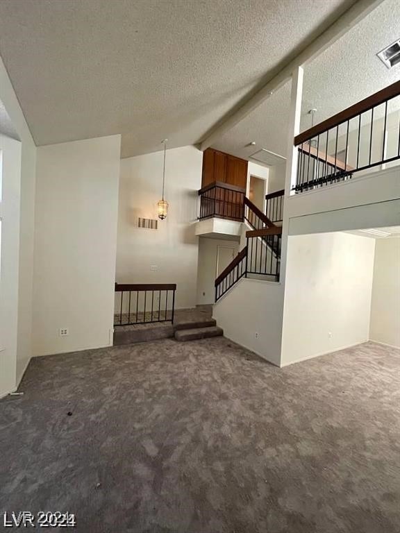 unfurnished living room with beam ceiling, a textured ceiling, carpet flooring, and high vaulted ceiling