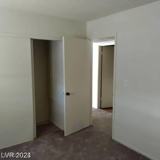 unfurnished bedroom featuring a closet and dark carpet