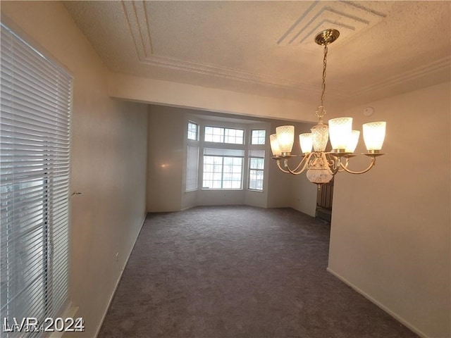 spare room featuring a raised ceiling, a textured ceiling, an inviting chandelier, and dark colored carpet