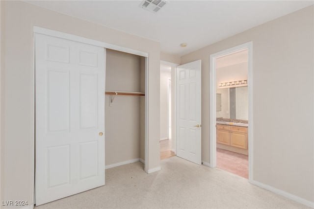 unfurnished bedroom with light carpet, a closet, ensuite bath, and sink