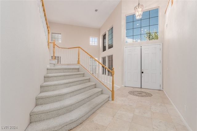 tiled entrance foyer with a towering ceiling, an inviting chandelier, and a healthy amount of sunlight