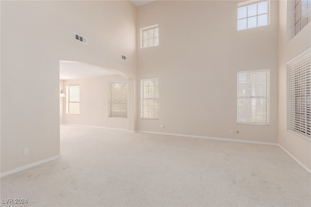 interior space featuring a towering ceiling and light carpet