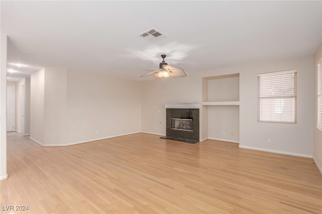 unfurnished living room with a fireplace, light wood-type flooring, and ceiling fan