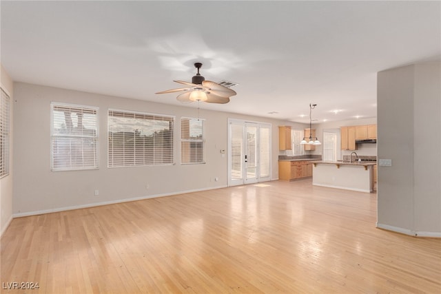 unfurnished living room featuring light hardwood / wood-style floors, sink, and ceiling fan