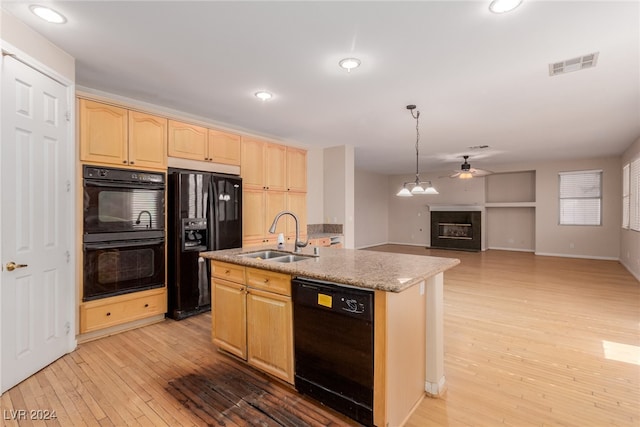 kitchen with black appliances, sink, pendant lighting, and a kitchen island with sink