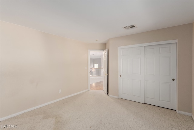 unfurnished bedroom featuring light carpet and a closet