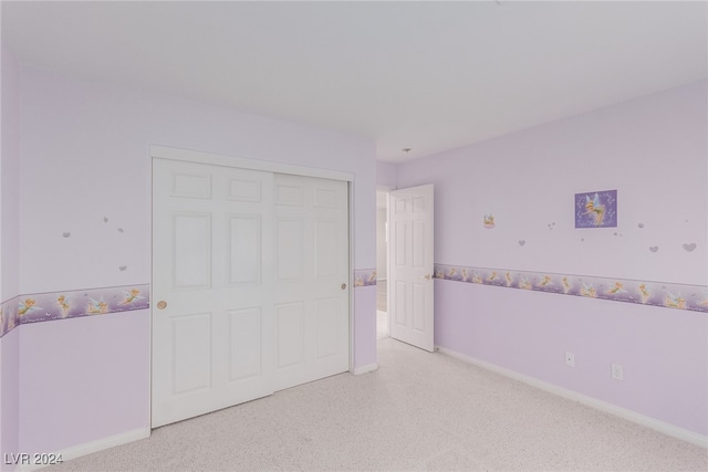 unfurnished bedroom with light colored carpet and a closet