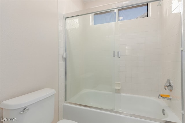 bathroom with combined bath / shower with glass door and toilet