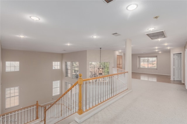 hallway featuring a chandelier and light carpet