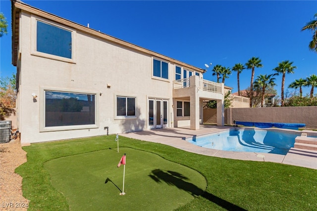 back of house with a patio, a covered pool, and a balcony