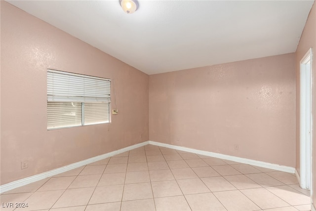 spare room with light tile patterned floors and lofted ceiling