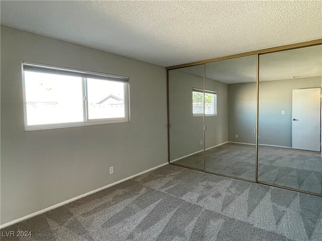 unfurnished bedroom with a closet, carpet, and a textured ceiling