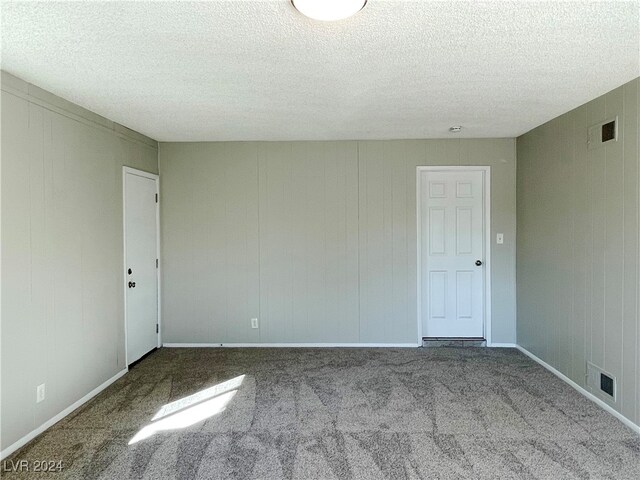 carpeted empty room with a textured ceiling