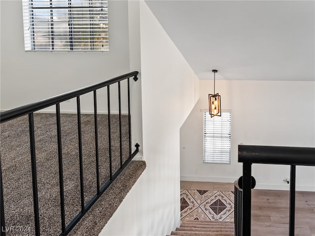 stairs with hardwood / wood-style floors and a notable chandelier