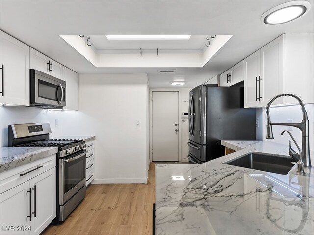 kitchen featuring white cabinets, a raised ceiling, light stone counters, and appliances with stainless steel finishes