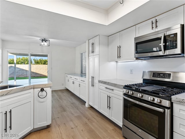 kitchen with sink, light stone countertops, light hardwood / wood-style floors, white cabinetry, and stainless steel appliances