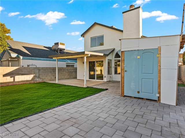 rear view of property featuring a lawn, cooling unit, and a patio