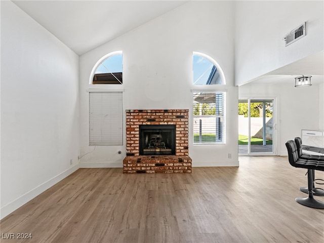 living room with a fireplace, light hardwood / wood-style flooring, and high vaulted ceiling