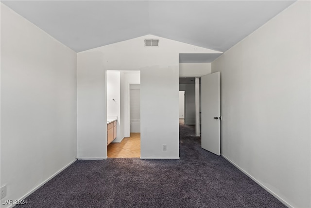 unfurnished bedroom featuring connected bathroom, light colored carpet, and lofted ceiling