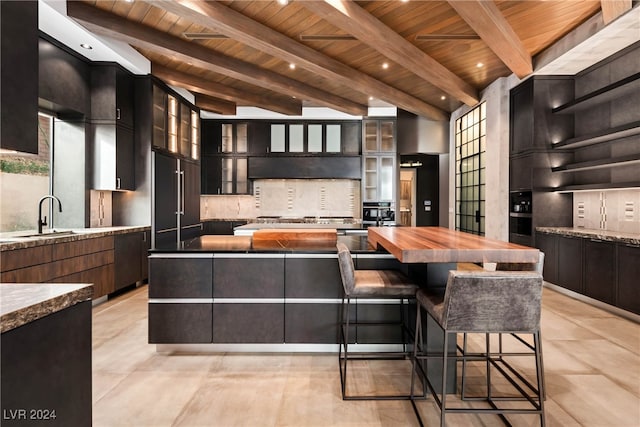 kitchen with beam ceiling, a kitchen island, wooden ceiling, and sink