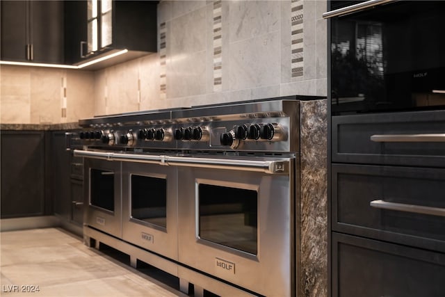 kitchen featuring black oven, range with two ovens, and stone counters