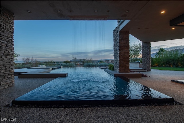 patio terrace at dusk featuring a water view