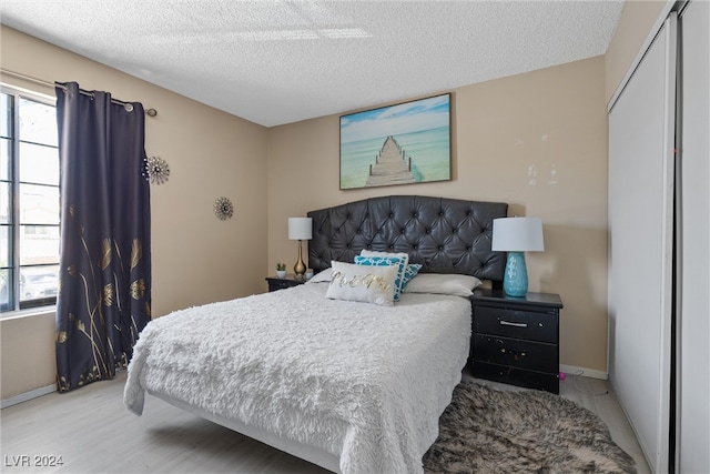 bedroom featuring a closet, a textured ceiling, and light hardwood / wood-style flooring