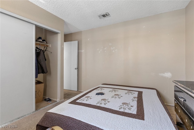 carpeted bedroom with a closet and a textured ceiling