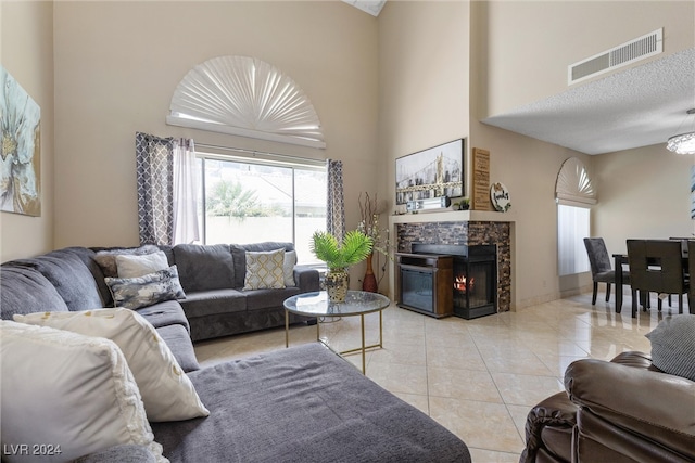 living room featuring light tile patterned flooring, a high ceiling, and a tile fireplace