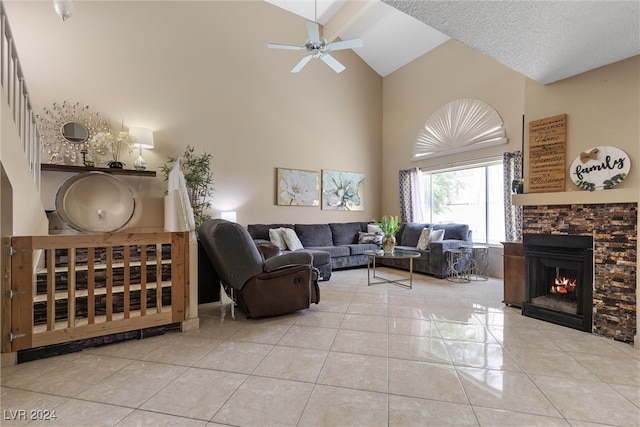 living room with a fireplace, a textured ceiling, ceiling fan, high vaulted ceiling, and light tile patterned floors