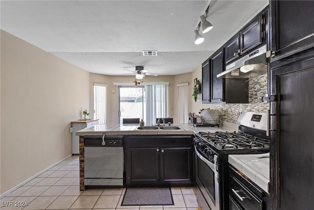 kitchen featuring kitchen peninsula, light tile patterned floors, a textured ceiling, sink, and stainless steel appliances