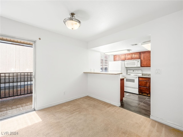 kitchen with dark colored carpet, white appliances, and plenty of natural light