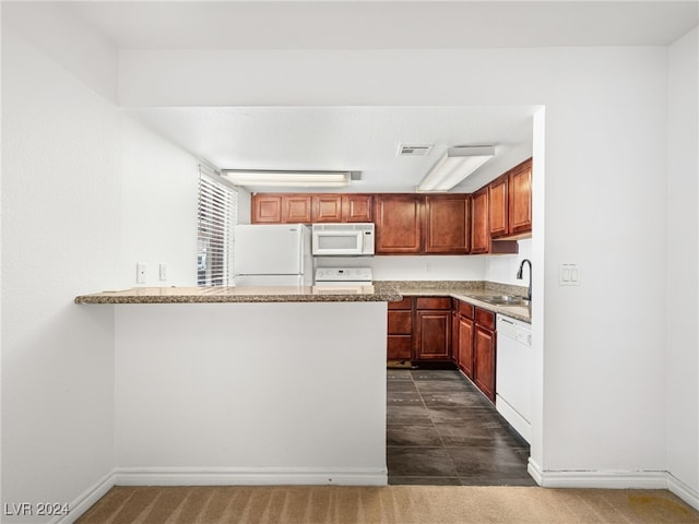 kitchen with kitchen peninsula, light stone countertops, white appliances, dark tile patterned floors, and sink