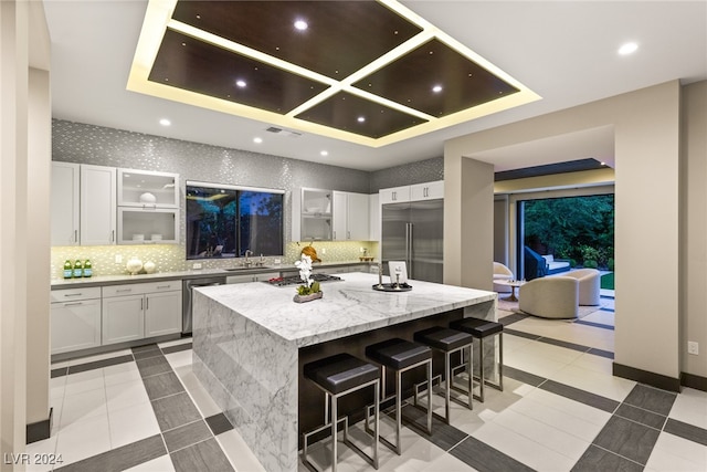 kitchen featuring tasteful backsplash, light stone countertops, a kitchen island, stainless steel appliances, and a breakfast bar