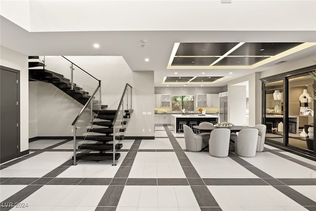 interior space with a tray ceiling and tile patterned flooring