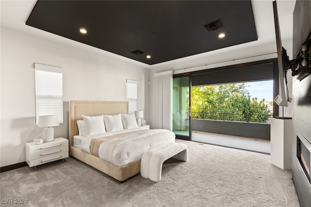 bedroom featuring access to exterior, carpet flooring, and a raised ceiling