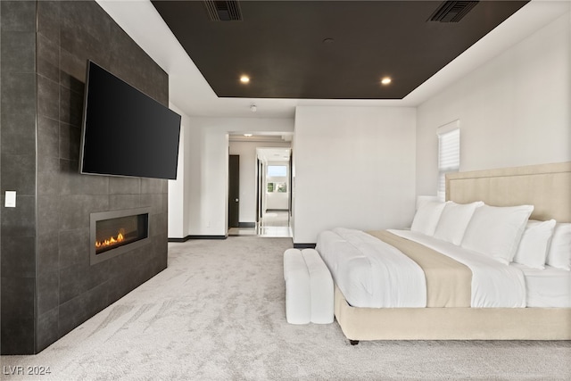 bedroom featuring a tiled fireplace, multiple windows, and carpet floors