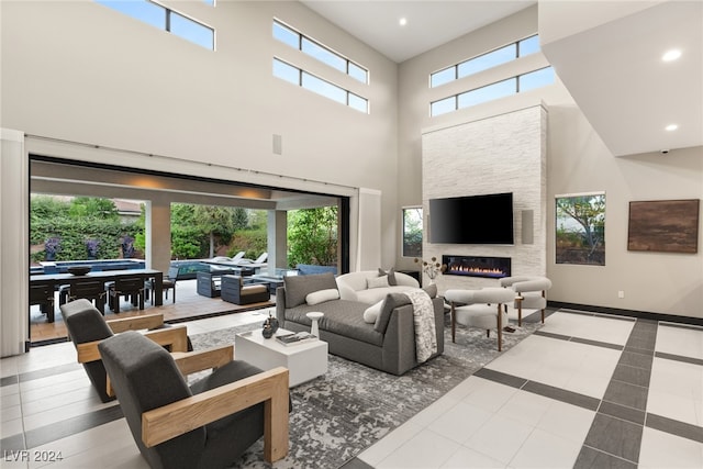 tiled living room featuring a fireplace, a healthy amount of sunlight, and a high ceiling