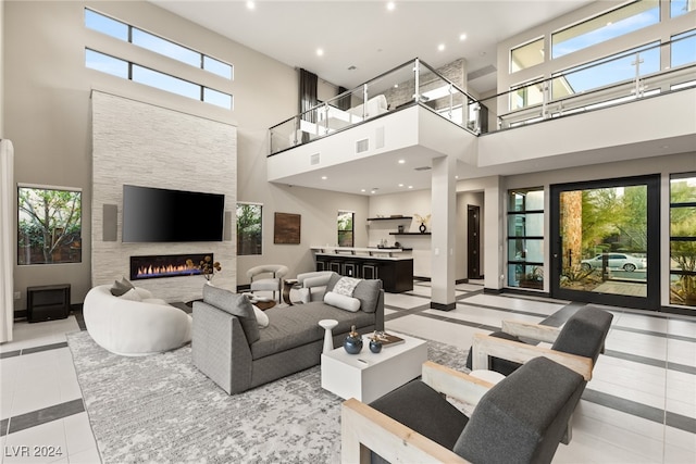 living room with a stone fireplace, a high ceiling, and a wealth of natural light