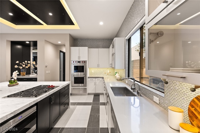 kitchen featuring sink, white cabinetry, decorative backsplash, and stainless steel double oven