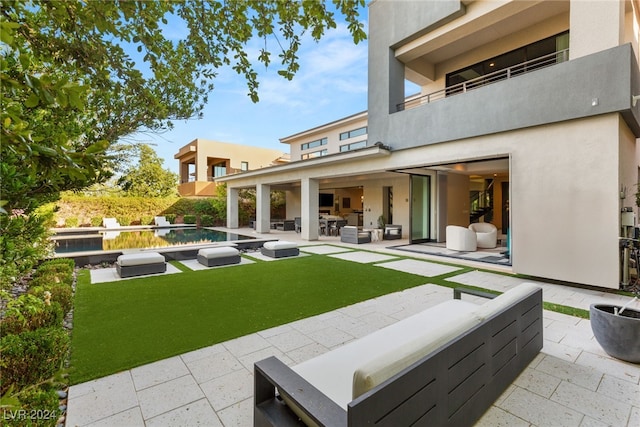 back of property featuring a patio area, a lawn, and a balcony