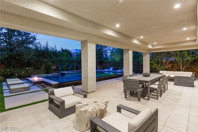 patio terrace at dusk featuring a swimming pool with hot tub and an outdoor hangout area