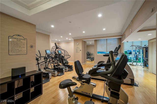 gym featuring crown molding and light wood-type flooring