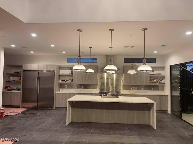 kitchen with high quality fridge, hanging light fixtures, tasteful backsplash, and a center island