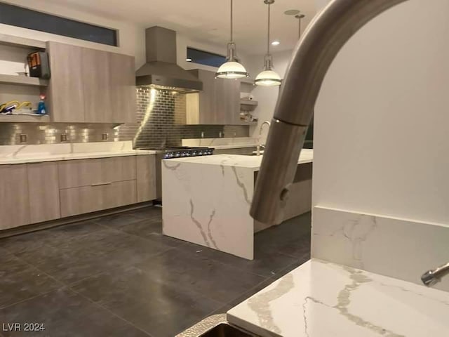 kitchen with wall chimney range hood, pendant lighting, backsplash, and light stone countertops