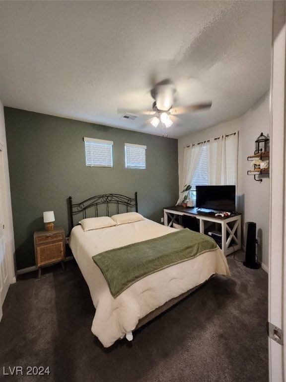 bedroom featuring dark carpet, a textured ceiling, and ceiling fan