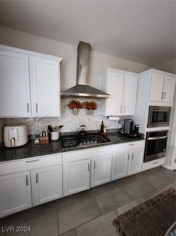 kitchen with white cabinetry, stainless steel appliances, wall chimney exhaust hood, and tasteful backsplash