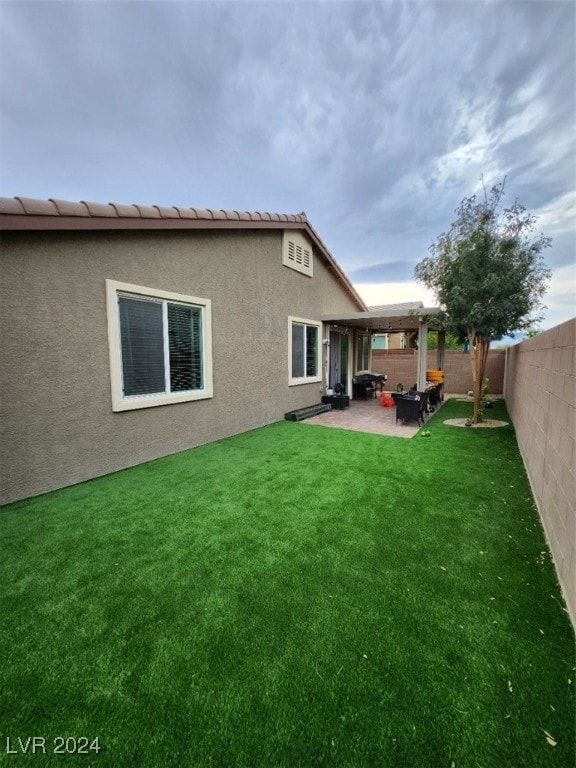 rear view of house featuring a yard and a patio area