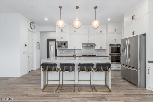 kitchen featuring white cabinets, an island with sink, hanging light fixtures, and appliances with stainless steel finishes