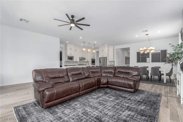 living room featuring light hardwood / wood-style floors and ceiling fan with notable chandelier